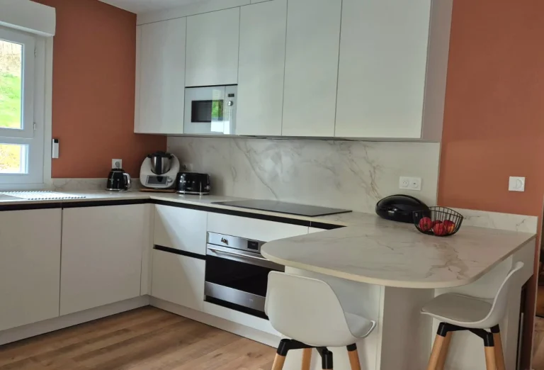 Retour de plan formant coin repas avec chaises devant un mur terracotta, réalisation MT Cuisine à Pompertuzat