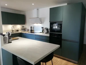 Cuisine à façades vert foncé avec îlot et plan de travail blanc, réalisation MT Cuisine à Toulouse