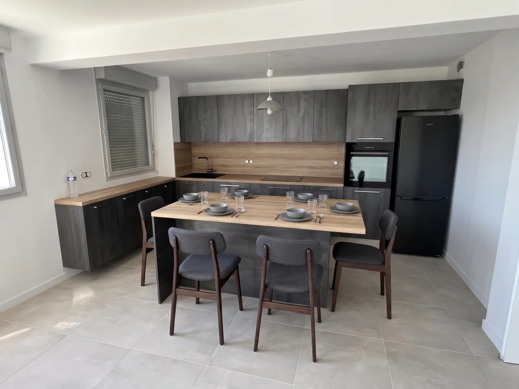 Îlot table en bois foncé avec chaises, crédence bois et réfrigérateur, réalisation MT Cuisine à Toulouse