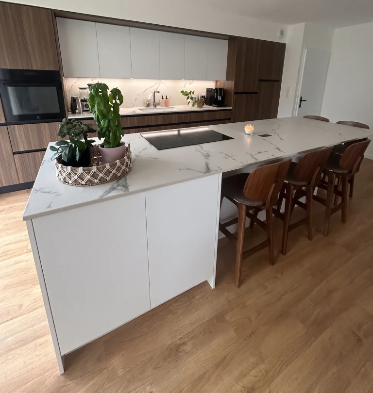 Îlot de cuisson en Dekton Kairos prolongé d’un plan repas, façades d’aspect noyer, réalisation MT Cuisine à Léguevin
