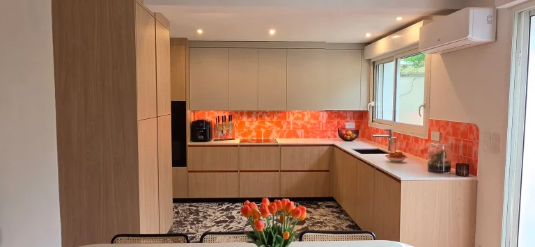 Cuisine en U à façades d'aspect chêne clair avec faïence orange et plan de travail clair, réalisation MT Cuisine à Toulouse