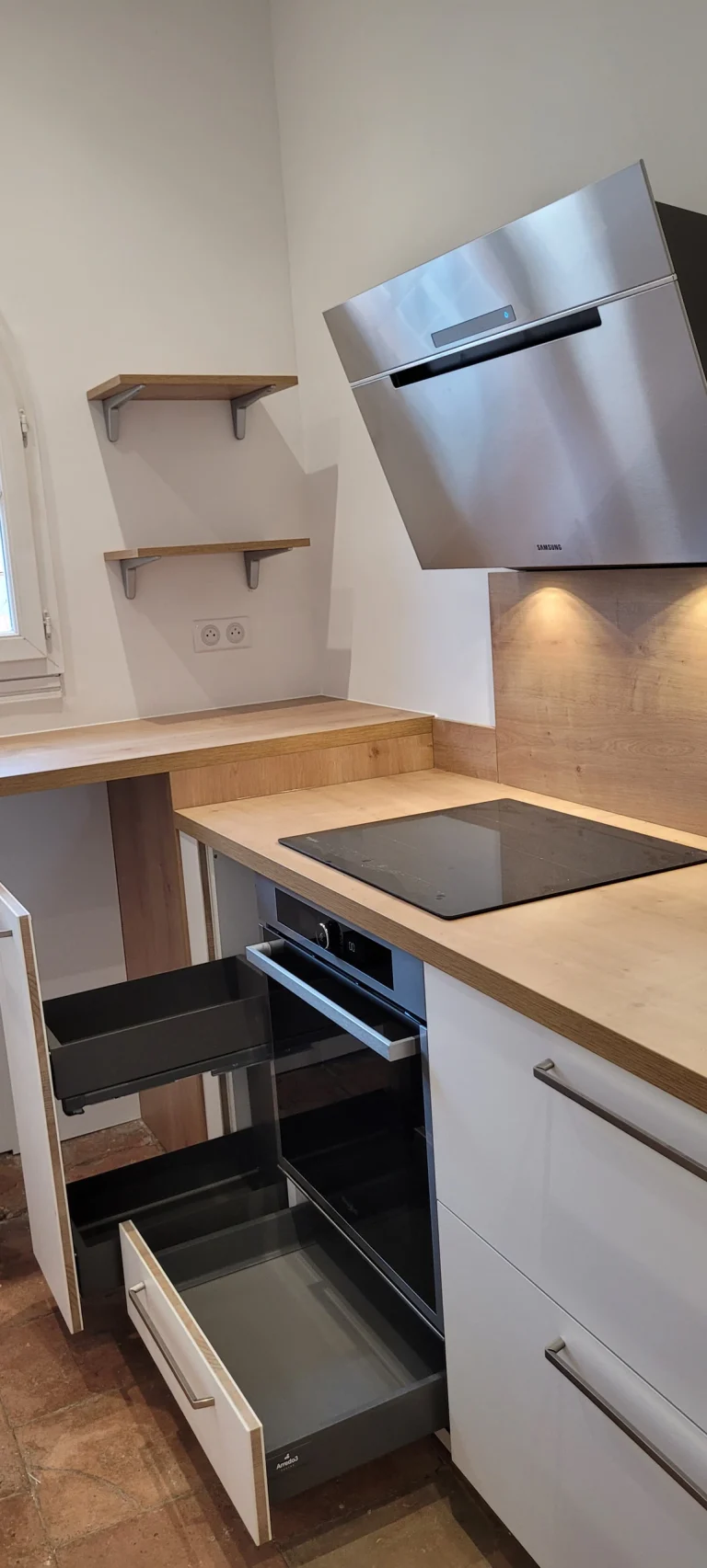 Plaque à induction, hotte inox et four encastré sous des étagères murales, réalisation MT Cuisine à Toulouse
