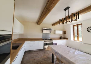 Cuisine blanche sous poutres apparentes avec piano de cuisson, réalisation MT Cuisine à Villemur-sur-Tarn