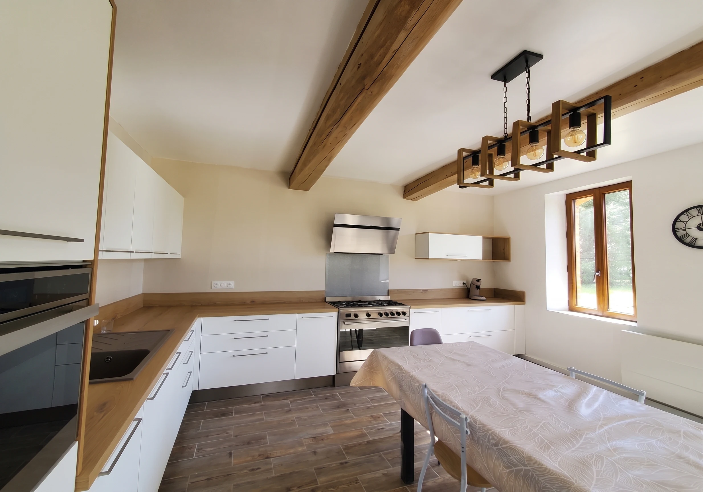Cuisine blanche sous poutres apparentes avec piano de cuisson, réalisation MT Cuisine à Villemur-sur-Tarn