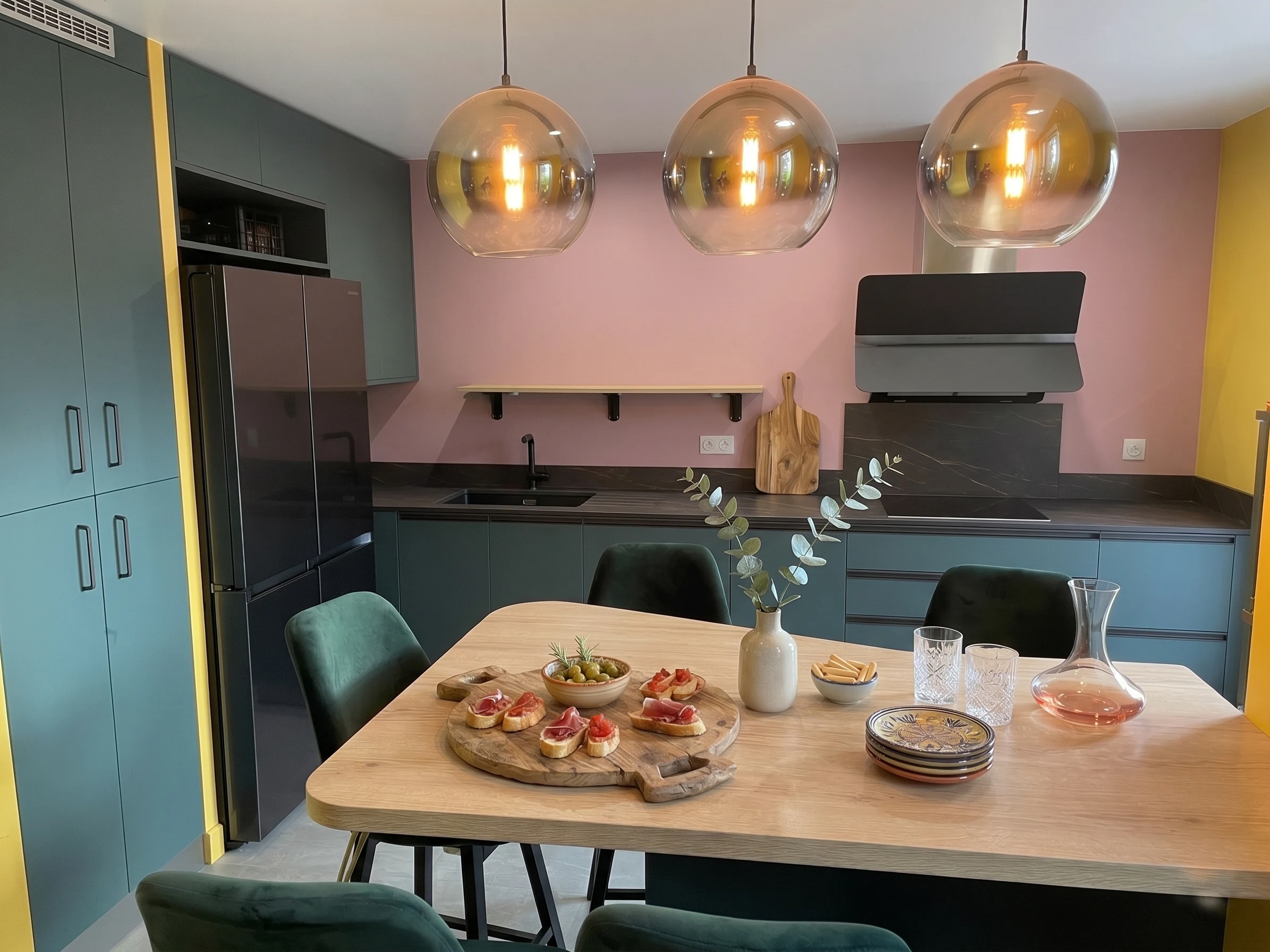 Coin repas éclairé par des suspensions en verre, réalisation MT Cuisine à Toulouse