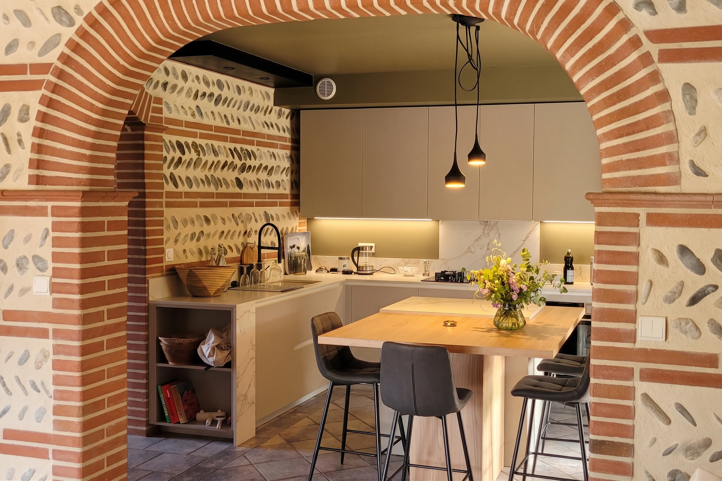 Table en plaquage de chêne et tabourets sous l’arche en brique, réalisation MT Cuisine à Plaisance-du-Touch