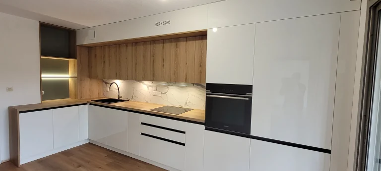 Cuisine en L à façades blanches brillantes avec four en colonne, réalisation MT Cuisine à Toulouse