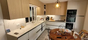 Cuisine avec plan de travail, colonnes de four et table ronde en bois, réalisation MT Cuisine à Plaisance-du-Touch