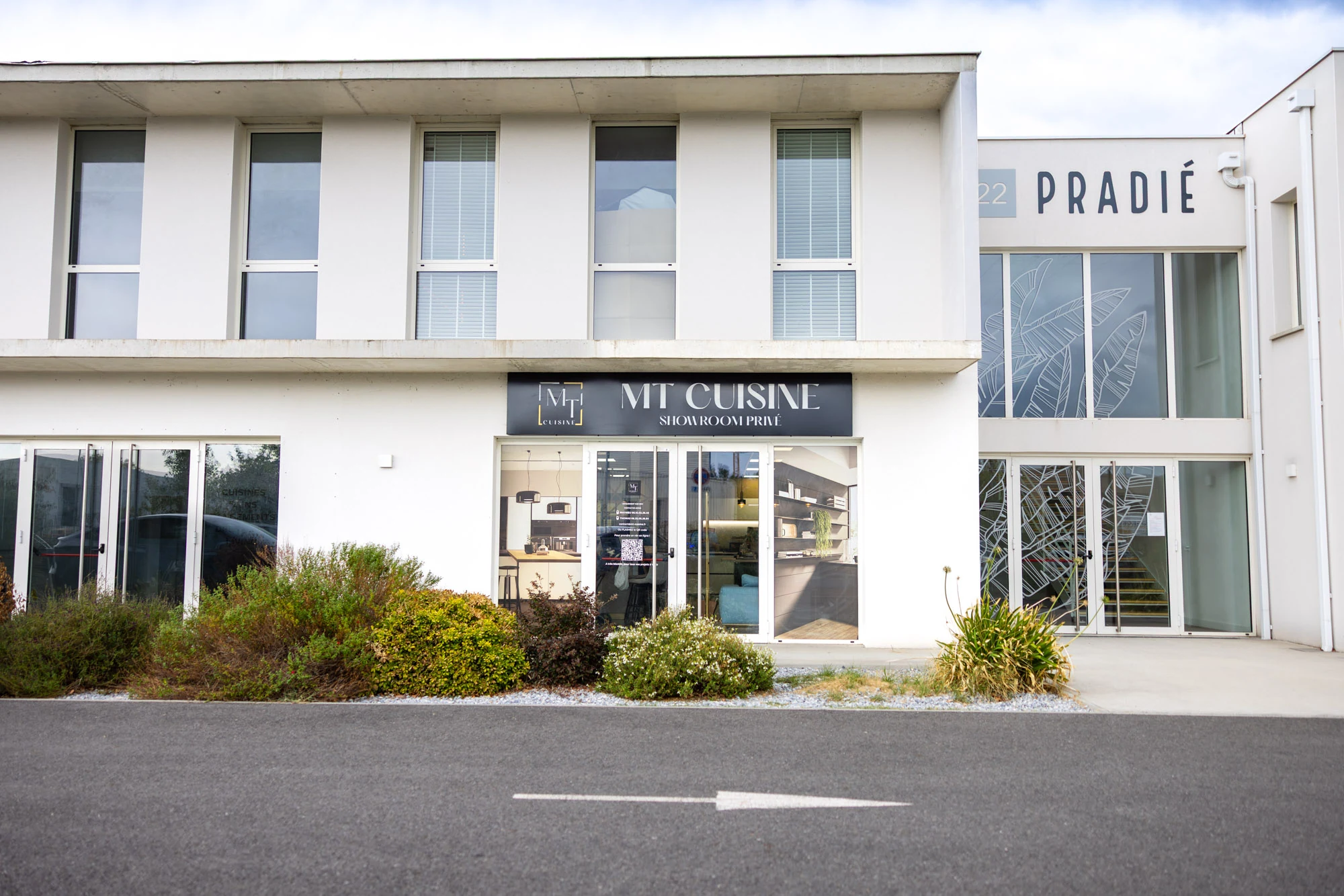 Façade blanche du showroom privé MT Cuisine à Portet-sur-Garonne, enseigne noire au-dessus de l'entrée vitrée