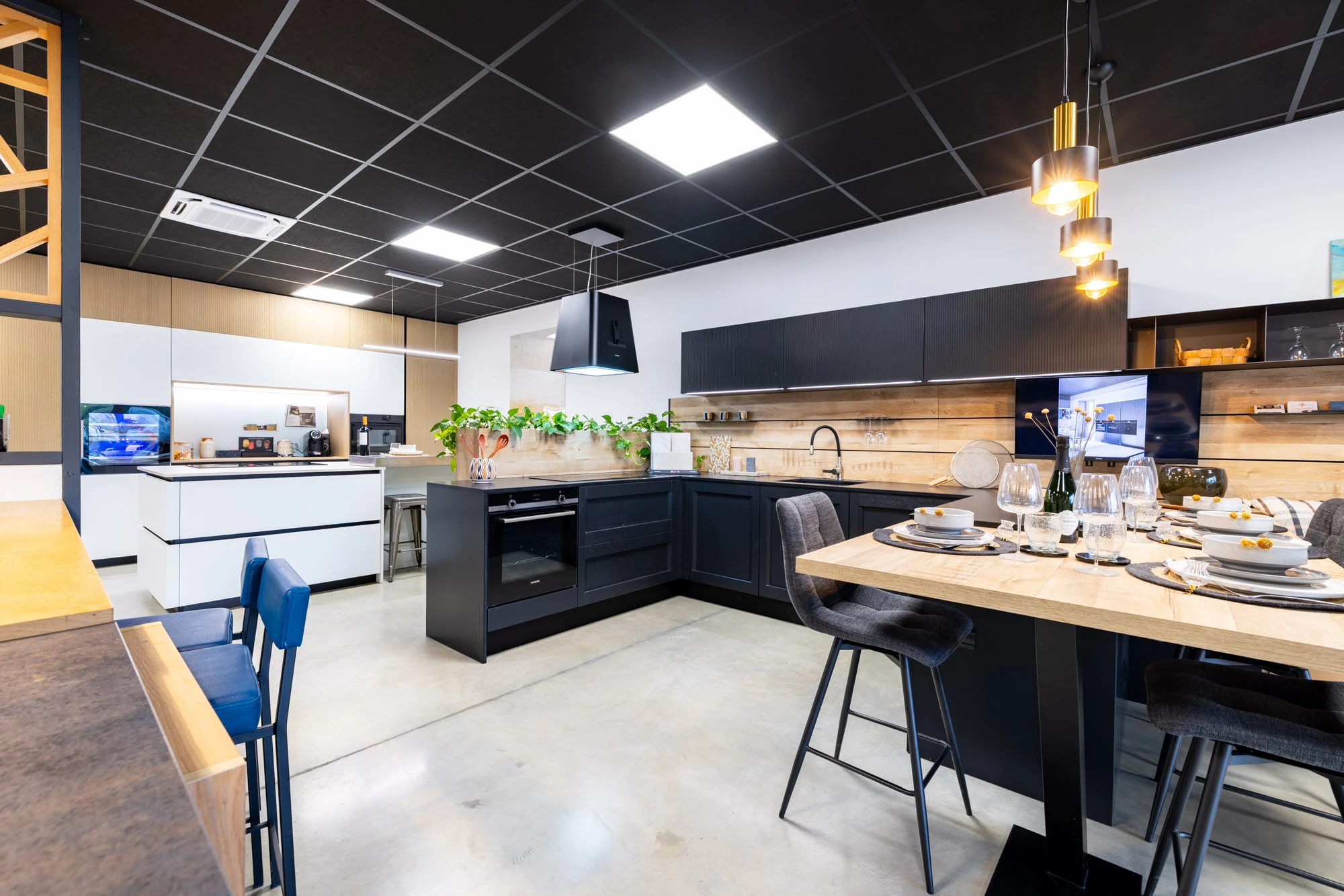 Vue d'ensemble du showroom de Portet-sur-Garonne, table haute dressée au premier plan et cuisines exposées en arrière-plan