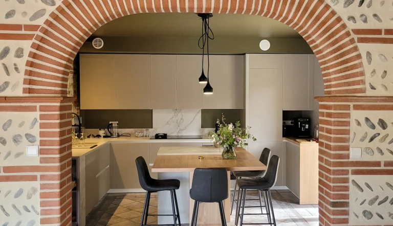 Îlot et table en plaquage de chêne naturel sous l’arche en brique toulousaine, réalisation MT Cuisine à Plaisance-du-Touch