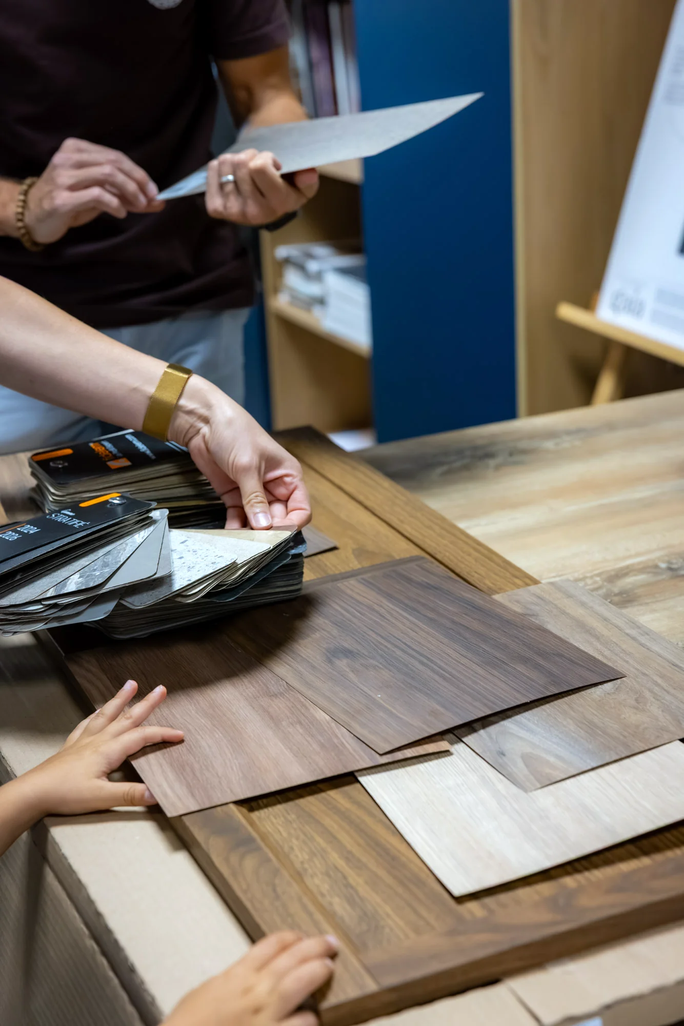 Mains comparant des échantillons de bois dans un tiroir de présentation au showroom MT Cuisine de Portet-sur-Garonne