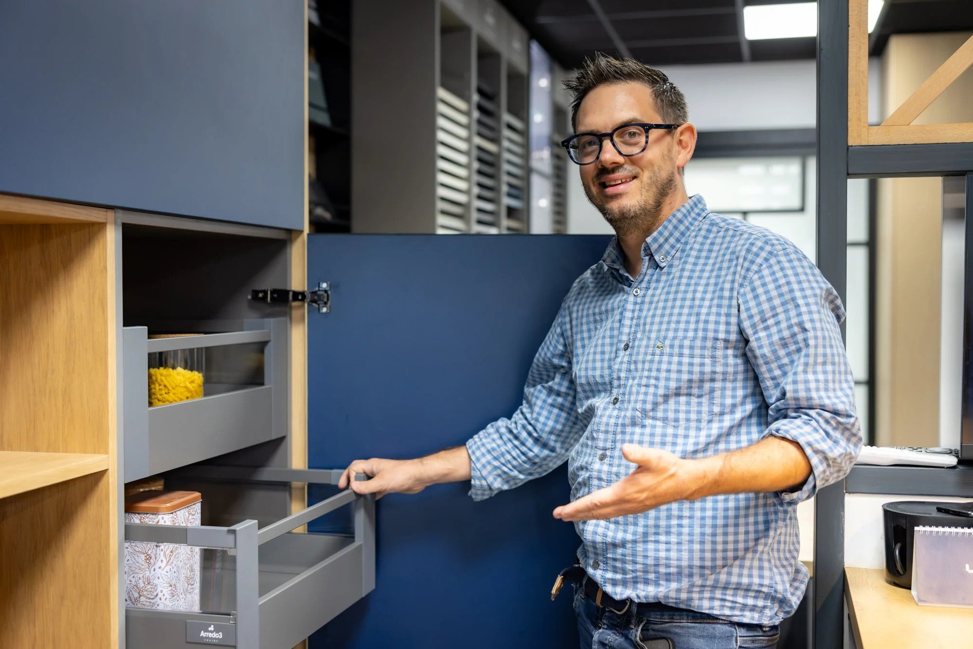 Thomas ouvre les tiroirs intérieurs d’une colonne bleue au showroom MT Cuisine de Portet-sur-Garonne