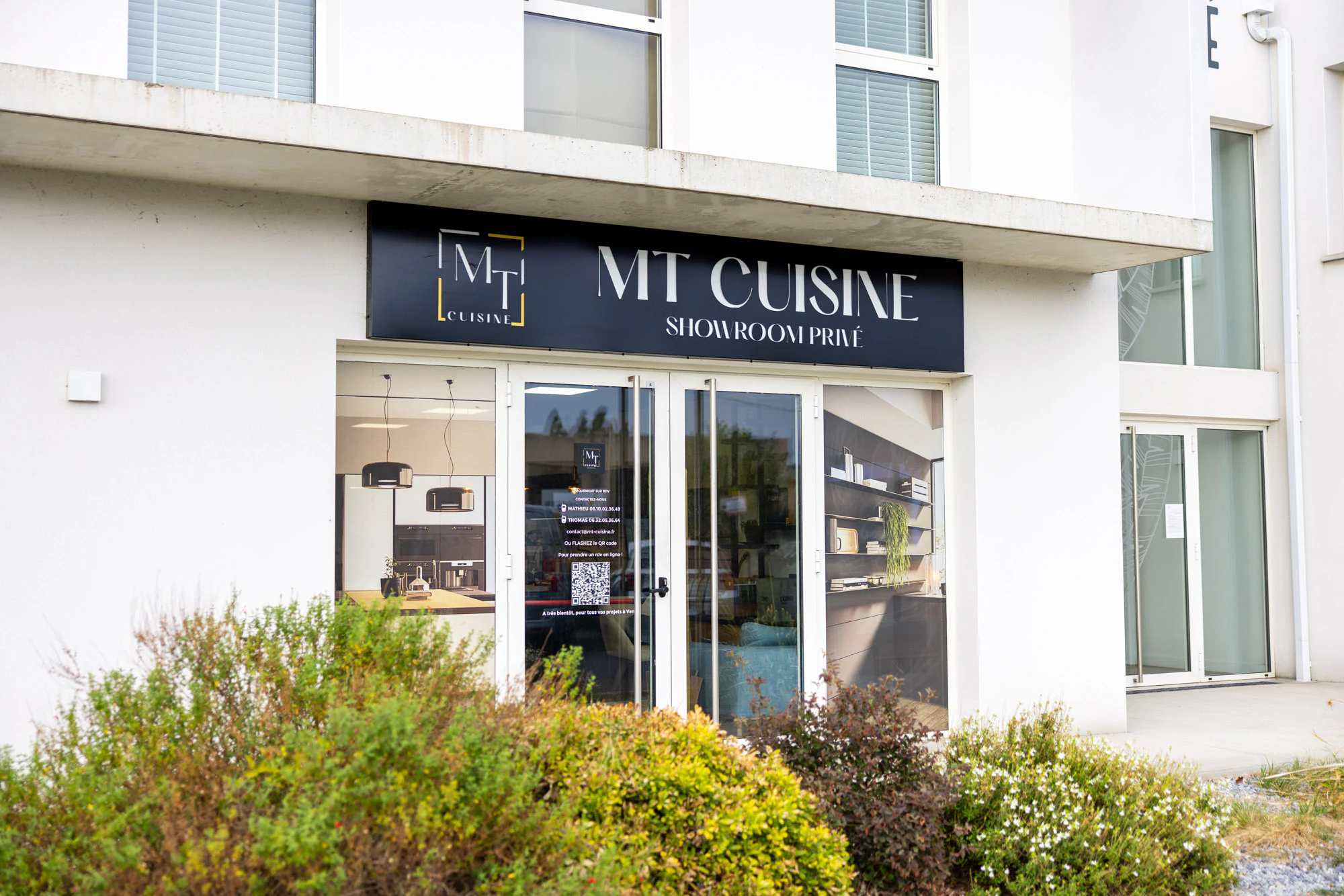 Entrée vitrée du showroom vue de trois quarts sous l'enseigne MT Cuisine, Portet-sur-Garonne