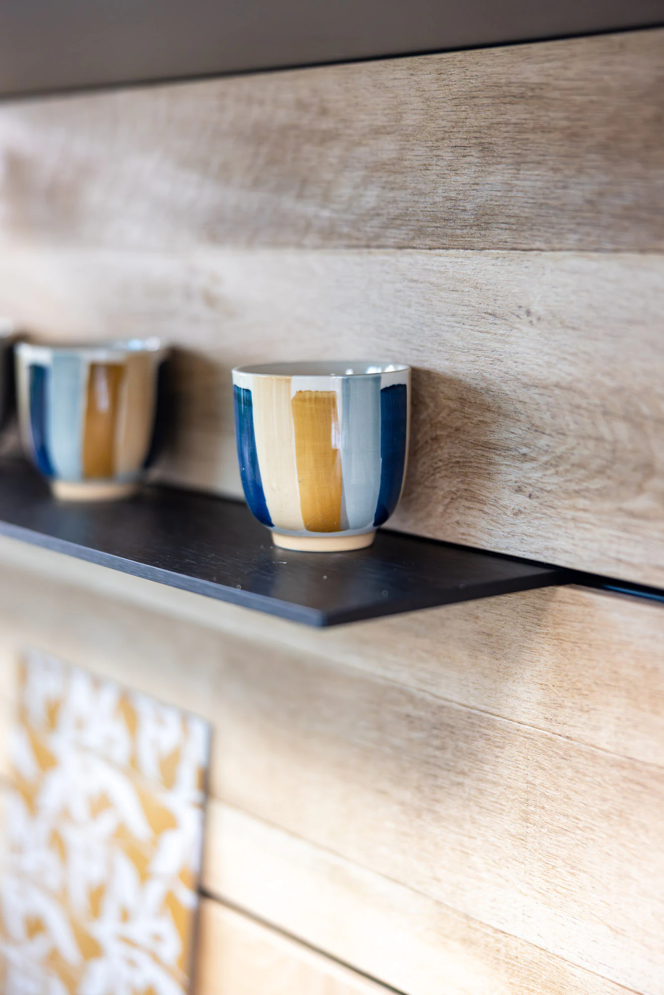 Crédence en lames de bois clair avec étagère noire et tasses posées, showroom MT Cuisine à Portet-sur-Garonne