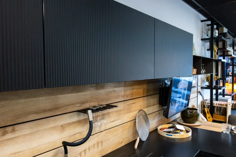 Meubles hauts anthracite à façades striées relevés au-dessus d'une crédence bois, showroom MT Cuisine à Portet-sur-Garonne