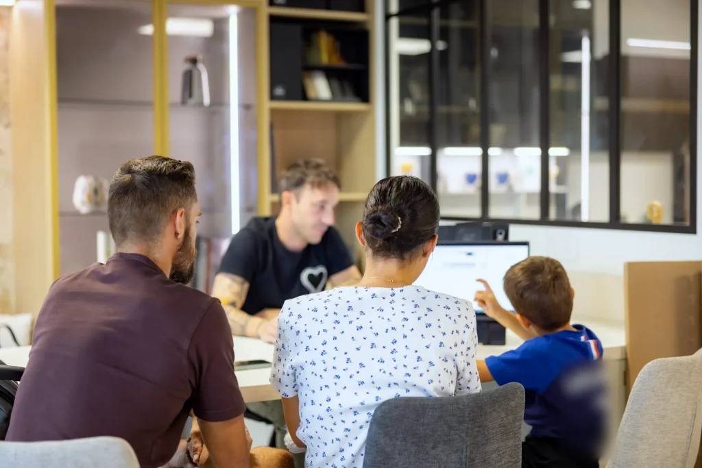 Rendez-vous de conception en famille avec Thomas devant l’écran au showroom MT Cuisine de Portet-sur-Garonne